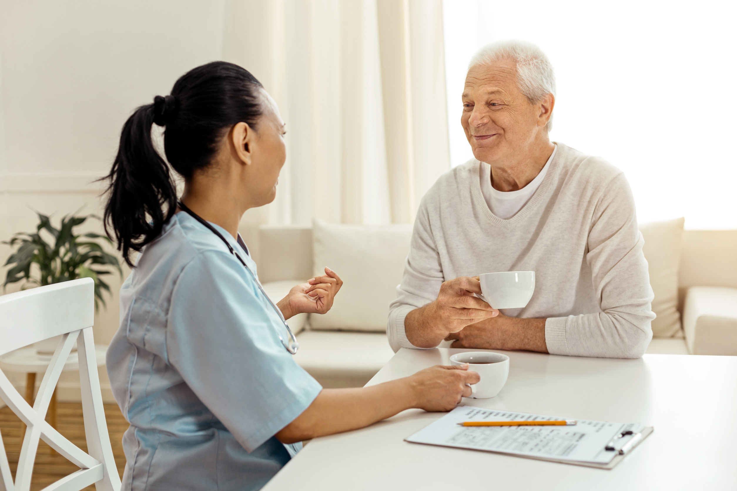 Positive nice caregiver and patient having tea